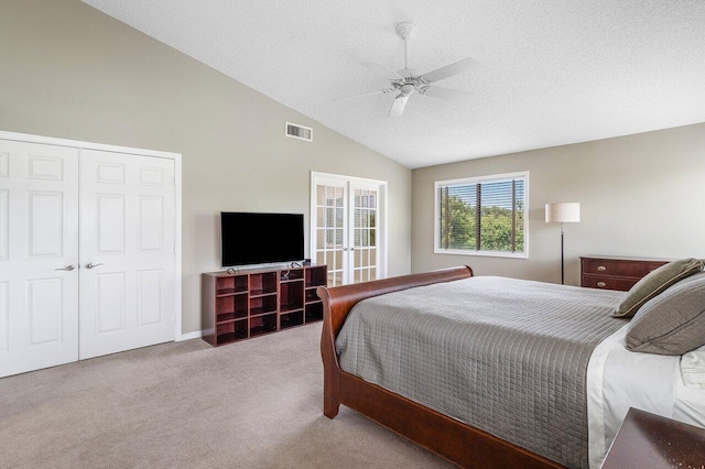 carpeted bedroom with a closet, a textured ceiling, vaulted ceiling, and ceiling fan