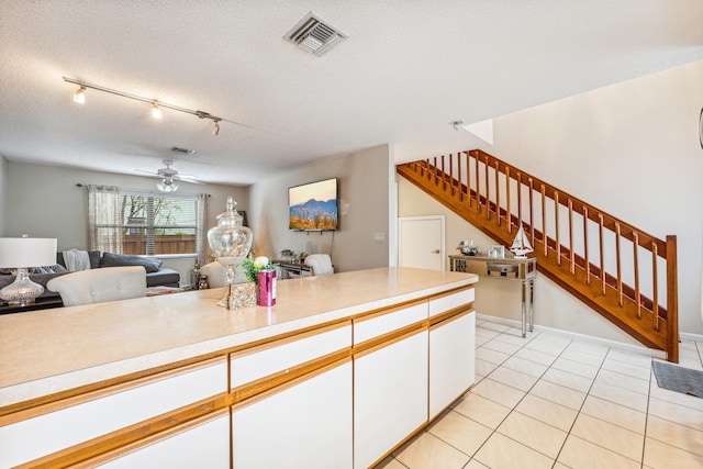 kitchen featuring ceiling fan, light tile patterned flooring, a textured ceiling, rail lighting, and white cabinetry