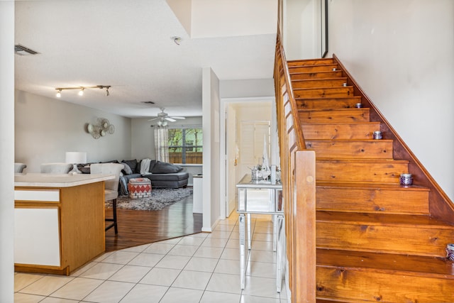 stairs featuring wood-type flooring, a textured ceiling, and ceiling fan