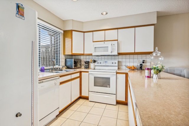 kitchen with light tile patterned flooring, white appliances, backsplash, white cabinets, and a textured ceiling