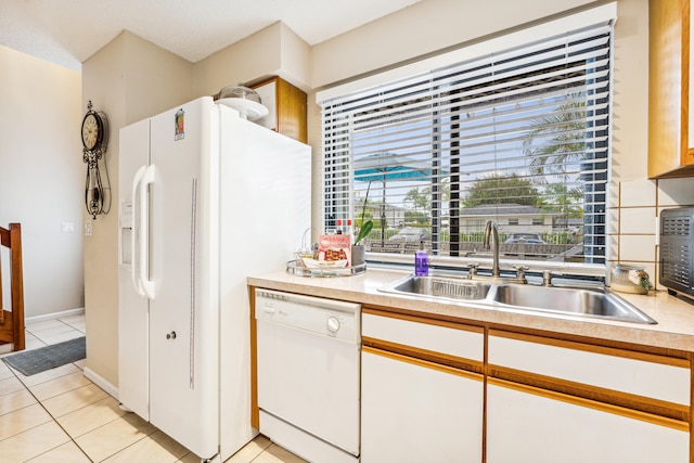 kitchen featuring white appliances, sink, light tile patterned floors, and white cabinetry