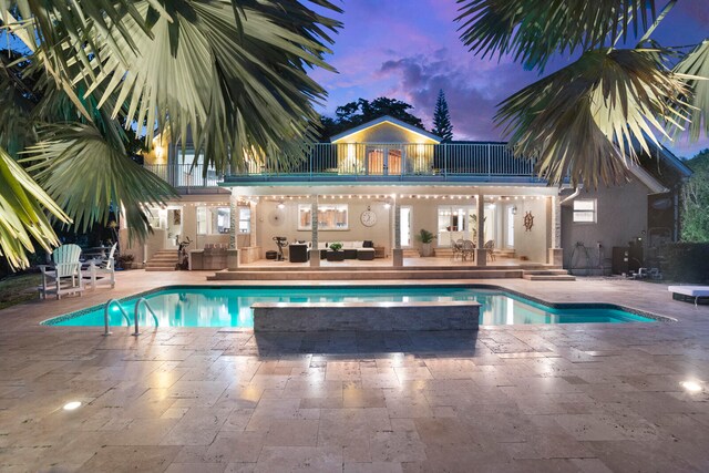 pool at dusk featuring a patio area