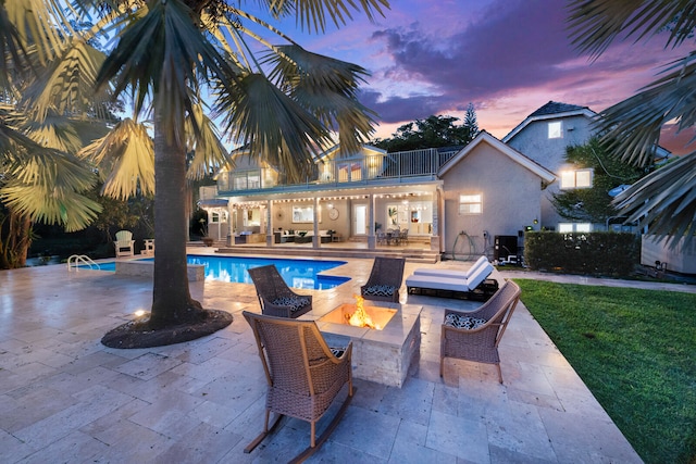 pool at dusk with a jacuzzi, a patio area, and an outdoor living space with a fire pit