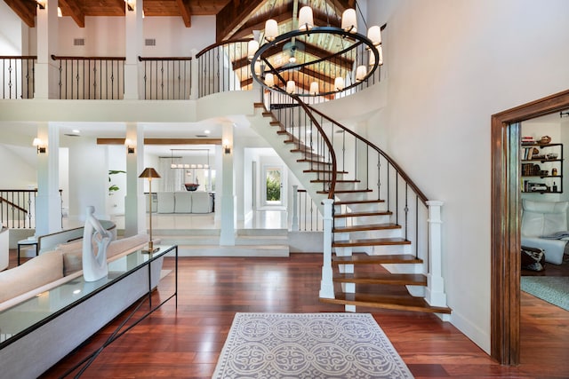 interior space with a notable chandelier, beam ceiling, a towering ceiling, and dark hardwood / wood-style floors