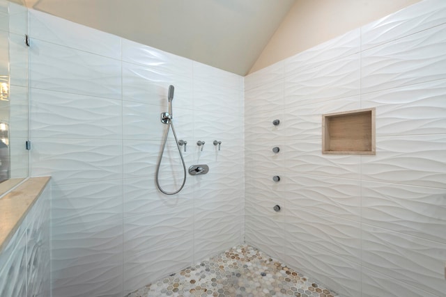 bathroom featuring lofted ceiling and tiled shower