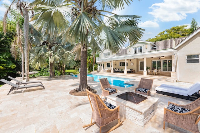 view of pool with ceiling fan, a fire pit, and a patio