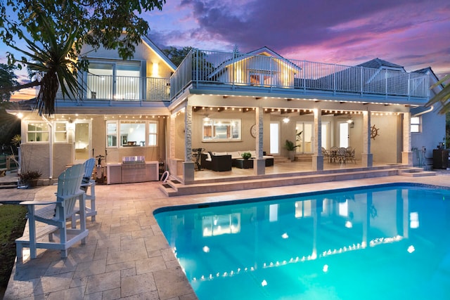 pool at dusk with an outdoor living space, a patio, area for grilling, and ceiling fan