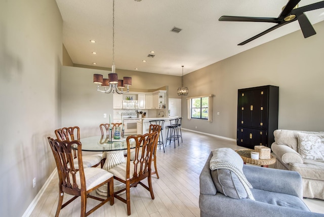 dining space with ceiling fan with notable chandelier and light hardwood / wood-style floors