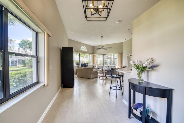 hall with light hardwood / wood-style flooring, a chandelier, and a textured ceiling