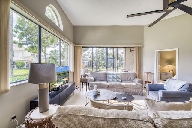 living room featuring plenty of natural light, ceiling fan, light wood-type flooring, and vaulted ceiling