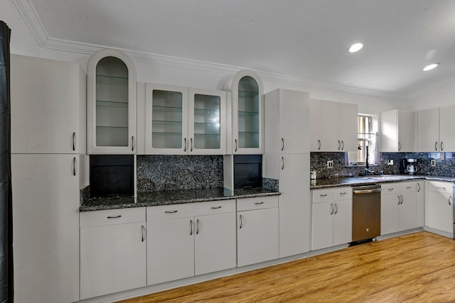 kitchen featuring light wood-type flooring, ornamental molding, tasteful backsplash, white cabinetry, and dark stone counters