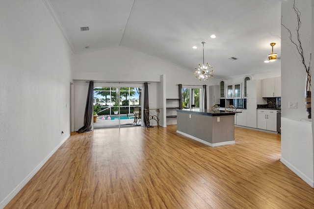 kitchen with white cabinets, crown molding, hanging light fixtures, light hardwood / wood-style flooring, and backsplash