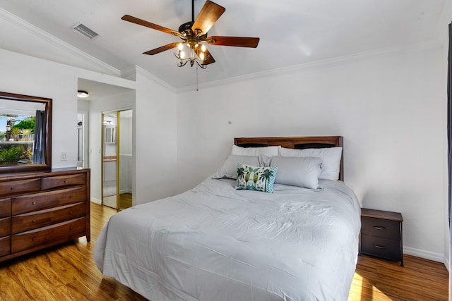 bedroom featuring light hardwood / wood-style floors, ensuite bathroom, ceiling fan, vaulted ceiling, and ornamental molding