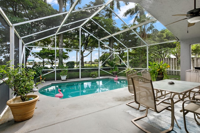 view of swimming pool with glass enclosure, a patio area, and ceiling fan