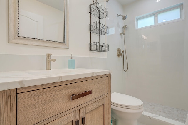 bathroom featuring a tile shower, vanity, and toilet