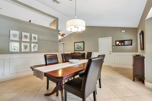 tiled dining space featuring ceiling fan with notable chandelier and vaulted ceiling