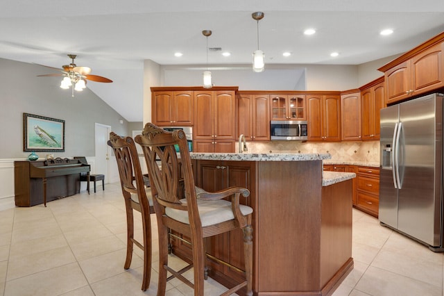 kitchen featuring light stone countertops, tasteful backsplash, hanging light fixtures, vaulted ceiling, and appliances with stainless steel finishes