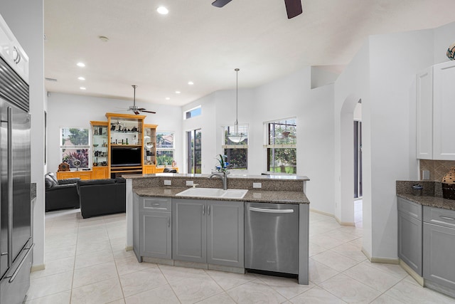 kitchen featuring a kitchen island with sink, gray cabinetry, sink, stainless steel appliances, and hanging light fixtures