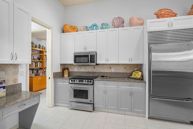 kitchen featuring dark stone counters, appliances with stainless steel finishes, decorative backsplash, and white cabinetry