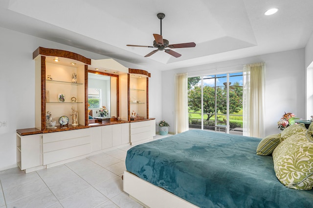 tiled bedroom with ceiling fan, a tray ceiling, and access to exterior