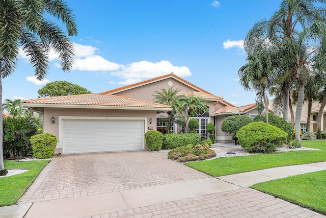 mediterranean / spanish-style home featuring a front lawn and a garage