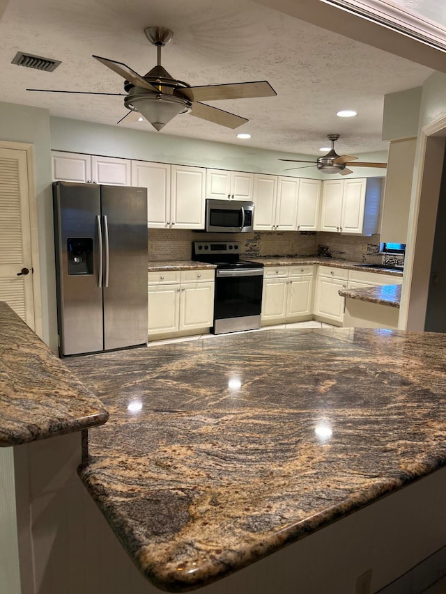 kitchen featuring stainless steel appliances, kitchen peninsula, and white cabinetry