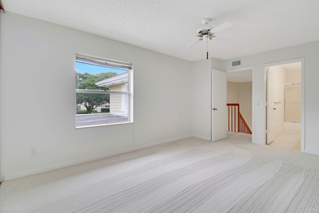 carpeted spare room featuring ceiling fan and a textured ceiling