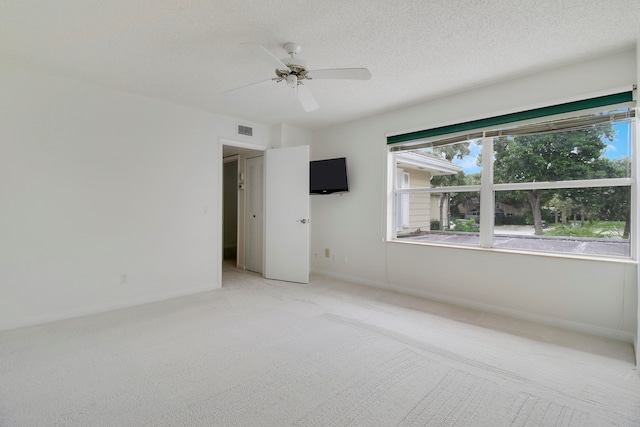 unfurnished bedroom featuring light carpet, ceiling fan, and a textured ceiling