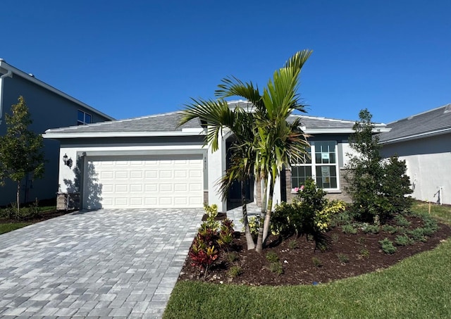 single story home featuring decorative driveway, an attached garage, and stucco siding