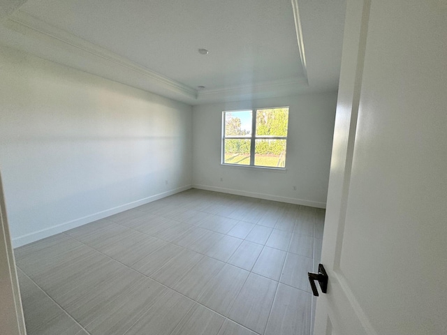 spare room with a raised ceiling, baseboards, and ornamental molding