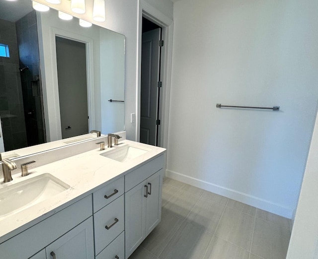 full bath featuring a sink, baseboards, double vanity, and a tile shower