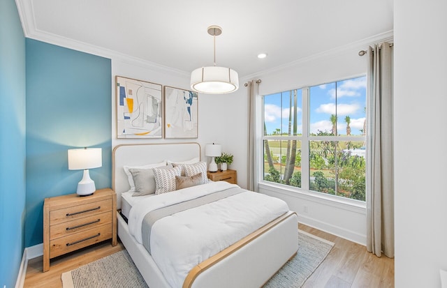 bedroom featuring crown molding, light wood-type flooring, and baseboards