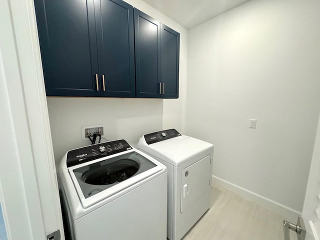 laundry room featuring washer and dryer, cabinet space, and baseboards