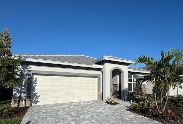 ranch-style house featuring stucco siding, an attached garage, and decorative driveway