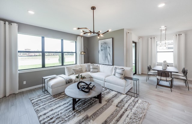 living area with light wood-style flooring, a notable chandelier, recessed lighting, and baseboards