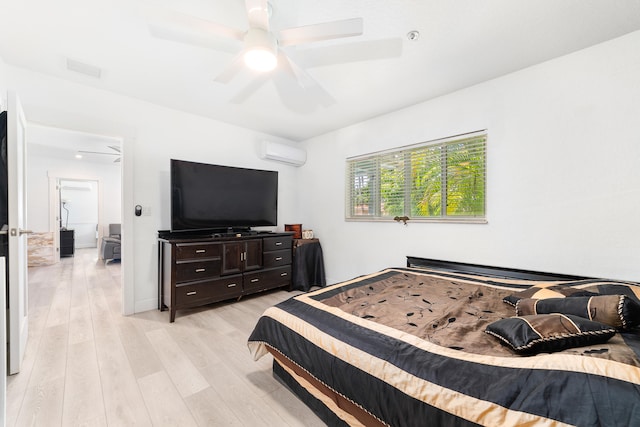 bedroom with an AC wall unit, light wood-type flooring, and ceiling fan