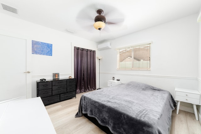 bedroom featuring a wall unit AC, ceiling fan, and light hardwood / wood-style floors