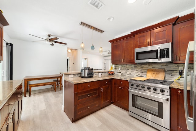 kitchen featuring pendant lighting, kitchen peninsula, appliances with stainless steel finishes, and light hardwood / wood-style flooring