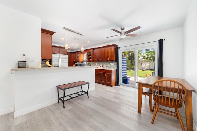 kitchen featuring decorative light fixtures, kitchen peninsula, stainless steel fridge with ice dispenser, and light hardwood / wood-style flooring