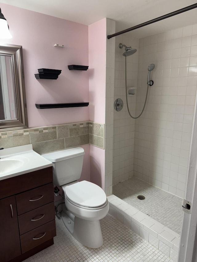 bathroom featuring tile patterned flooring, a tile shower, toilet, and tile walls