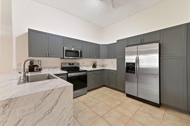 kitchen featuring gray cabinetry, light tile patterned flooring, sink, and stainless steel appliances