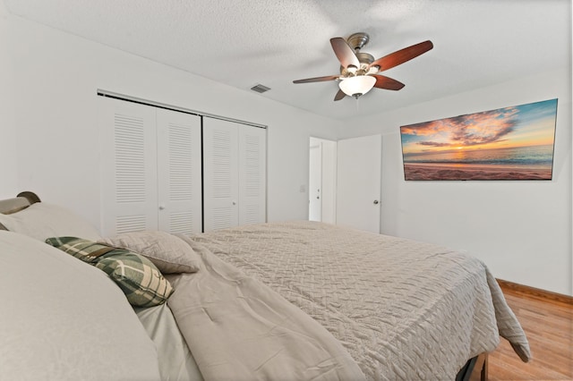 bedroom with ceiling fan, a closet, wood-type flooring, and a textured ceiling