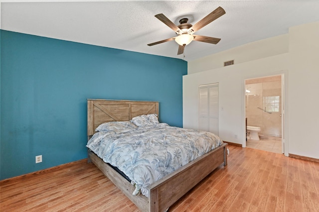 bedroom featuring ceiling fan, light hardwood / wood-style flooring, ensuite bathroom, a textured ceiling, and a closet