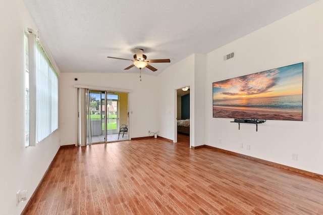 unfurnished living room with a textured ceiling, light wood-type flooring, ceiling fan, and lofted ceiling