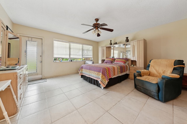 bedroom featuring ceiling fan, light tile patterned flooring, and a textured ceiling