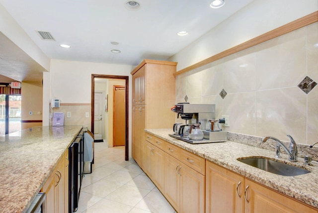 kitchen featuring light stone countertops, sink, light brown cabinets, light tile patterned floors, and tile walls