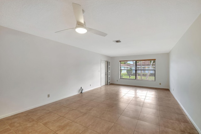 empty room with a textured ceiling, ceiling fan, and light tile patterned flooring