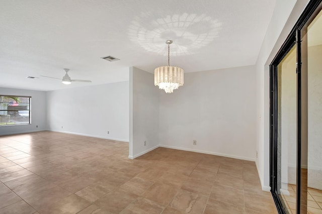 empty room featuring ceiling fan with notable chandelier