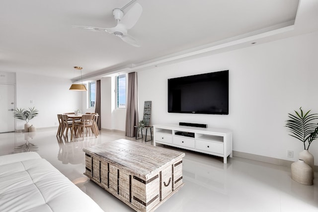 living area featuring a ceiling fan and baseboards