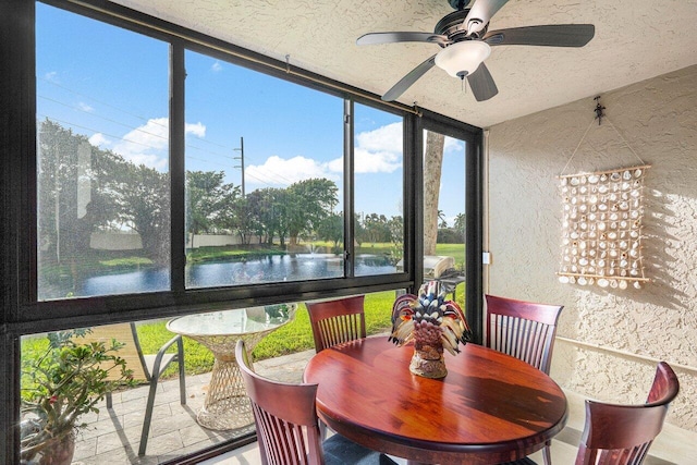 sunroom featuring ceiling fan, a healthy amount of sunlight, and a water view